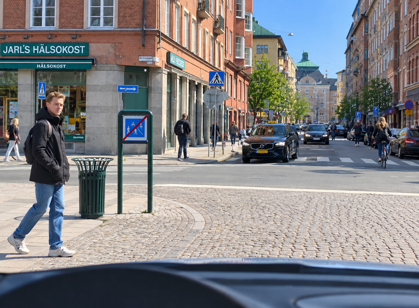 Gathörn i stadsmiljö med en fotgängare på väg att korsa gatan, vid skylten som markerar slutet på ett gångfartsområde.